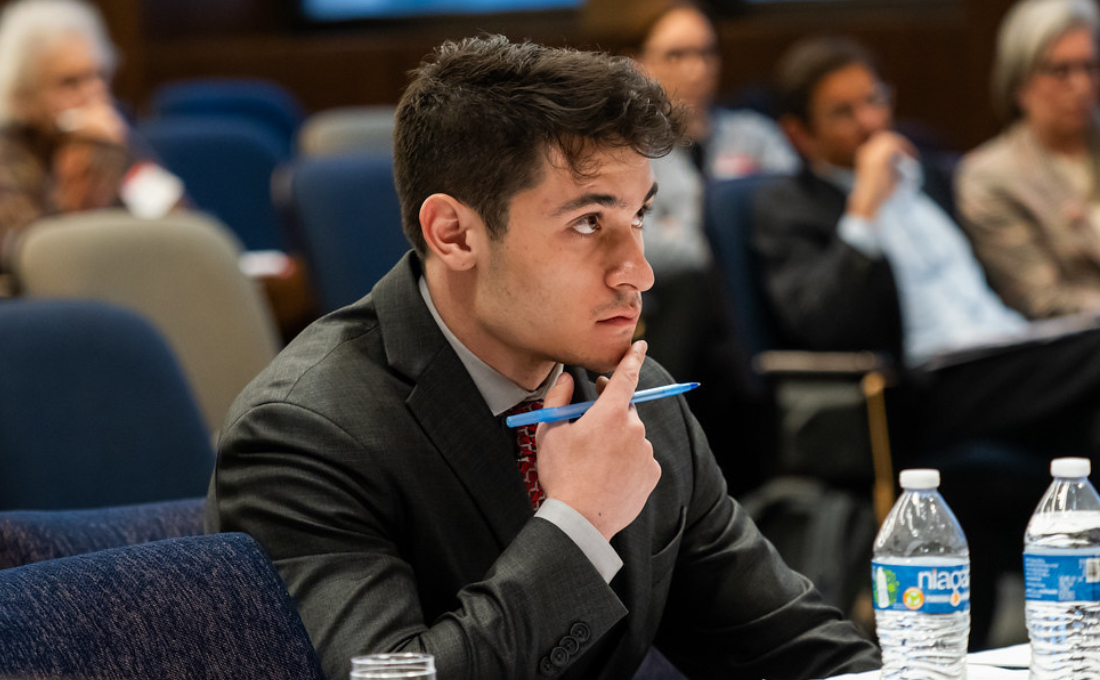 Man with light skin and brown hair in a suit in the Moot Court Room